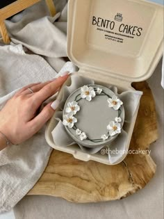 a woman's hand reaching for a cake in a box on top of a table