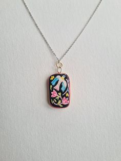 a necklace with a bird and flowers on it