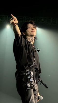 a man standing on top of a stage with his arms in the air and lights behind him