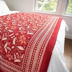 a red and white bedspread on a bed in a room with wooden floors