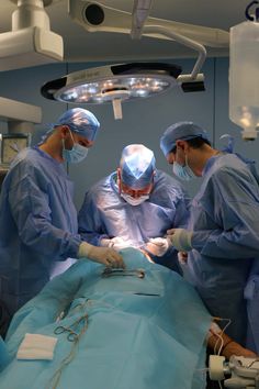 three doctors performing surgery on a patient in an operating room with lights and medical equipment