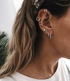 a woman with long hair wearing silver ear cuffs