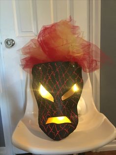 a black mask with yellow eyes and red hair