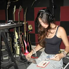 a woman sitting on the floor with headphones around her neck and looking at an electronic device