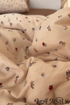 an unmade bed with white sheets and floral print on it, next to pillows