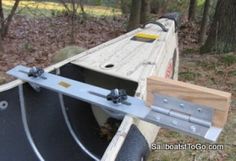 the back end of a wooden boat with metal brackets on it's side in the woods