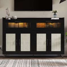 a tv mounted on the wall above a black cabinet with glass doors and shelves in front of it