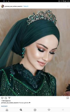 a woman wearing a green dress with a tiara on her head and veil over her head