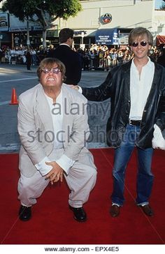 two men sitting on the red carpet at an event, one with his arm around the other