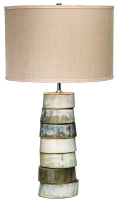 a lamp that is sitting on top of a table next to a white wall with a beige shade