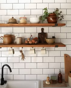 two wooden shelves filled with pots and pans on top of a white tiled wall