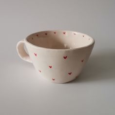 a white cup with red hearts on the inside is sitting on a gray table top