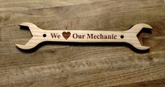 a wooden sign that says we love our mechanic with a wrench shaped like a dog bone