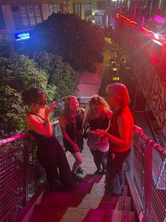 three girls are standing on the stairs looking at their cell phones