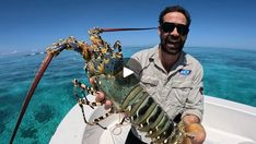 a man on a boat holding up a lobster