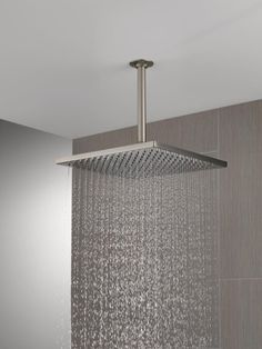 an overhead shower head with rain running down it's side and the wall behind it