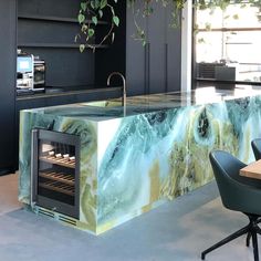 a kitchen counter with an oven in the center and chairs around it, next to a potted plant