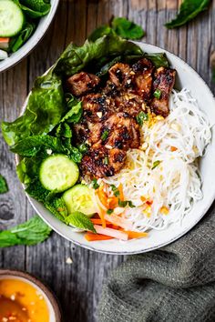 a white bowl filled with meat and veggies on top of a wooden table