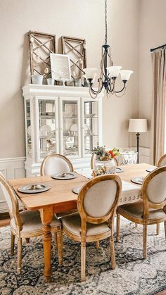 a dining room table with chairs and a chandelier above it in front of a window