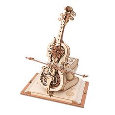 a wooden model of a violin on top of a sheet music box with an intricate design