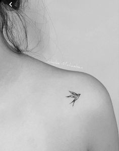 the back of a woman's shoulder with a small bird tattoo on her left shoulder