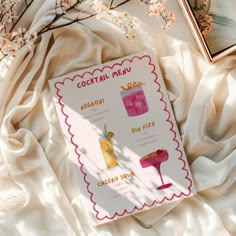 the cocktail menu is displayed on a white sheet with pink flowers and branches in the background