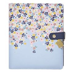 a blue and yellow flowered notebook with a gold tag on the front cover that says,