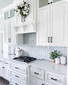 a kitchen with white cabinets and marble counter tops, an oven and stove top in the center