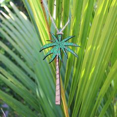 an ornament hanging from a palm tree in the jungle with green leaves behind it