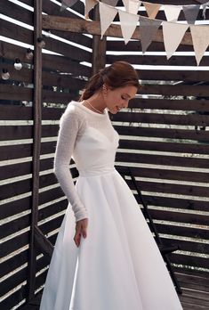 a woman in a white wedding dress standing on a wooden deck with bunting and flags