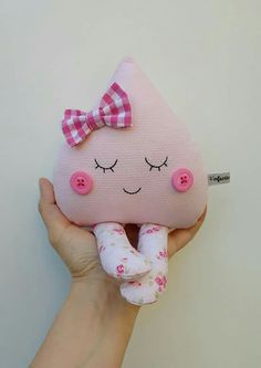 a hand holding a pink stuffed animal with a bow on it's head and eyes