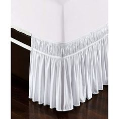 a white bed skirt with ruffles on the top and bottom, in front of a wooden floor