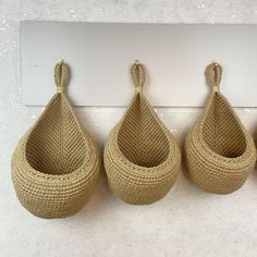 three woven baskets hanging from hooks on the wall