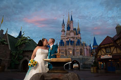 a bride and groom kissing in front of the castle at disney's magic kingdom