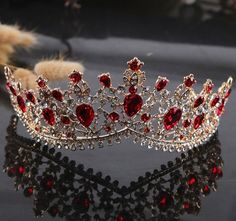 a tiara with red stones is shown on a black surface