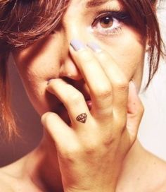 a woman with braids on her head is holding her hand to her face and looking at the camera