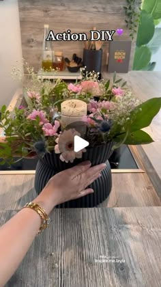 a woman is placing flowers in a vase on top of a table with the words action diy