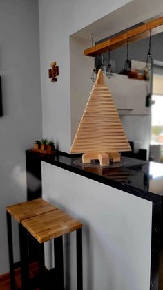 a small wooden christmas tree sitting on top of a counter next to two stools