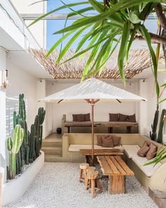 an outdoor living area with couches, table and umbrella