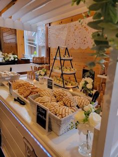 a buffet with breads, pastries and flowers on the counter at a wedding