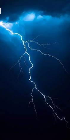 lightning strikes across the night sky with dark clouds and bright blue lightening in the background