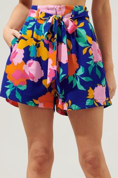 Spend the day basking in the sun, wearing these fitting shorts. Fun colored floral motifs against a blue-ground decorate these breezy shorts that sit high on the hips. A belt is added for a refined feminine look, while the shorts start to widen. They maintain a relaxed fit throughout the hips and thighs.- Hook and clasp- Zipper fly- Pockets- Bubble crepe- Color: Cobalt Pink OrangeSize + Fit - Model is 5'8" and wearing size XS- Measurements taken from size S - Waist: 13"- Inseam: 3" Fabric Self:9 Multicolor Beachwear Shorts For Summer Outings, Blue Tropical Print Beachwear Shorts, Blue Summer Shorts With Elastic Waistband, Spring Vacation Shorts, Vibrant Blue Bottoms For Vacation, Multicolor Shorts For Summer Outings, Blue Summer Shorts, Spring Beachwear Shorts, Summer Blue Shorts