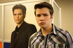 a young man standing in front of a portrait of him and another person behind him