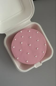 a pink cake in a white box with hearts on it's lid and inside