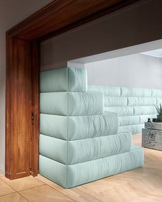 a stack of blue sheets sitting on top of a wooden floor next to a plant