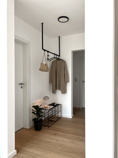 a coat rack with two coats hanging from it's hooks and a potted plant next to it