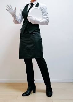 a woman dressed in black holding a white frisbee on her right hand and wearing an apron