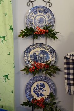 three plates are hanging on the wall with holly and red berries in front of them