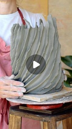 a woman is holding a clay sculpture with her hands on top of it and looking at the camera