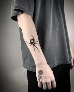 a person with a spider tattoo on their left arm and the other hand holding a flower